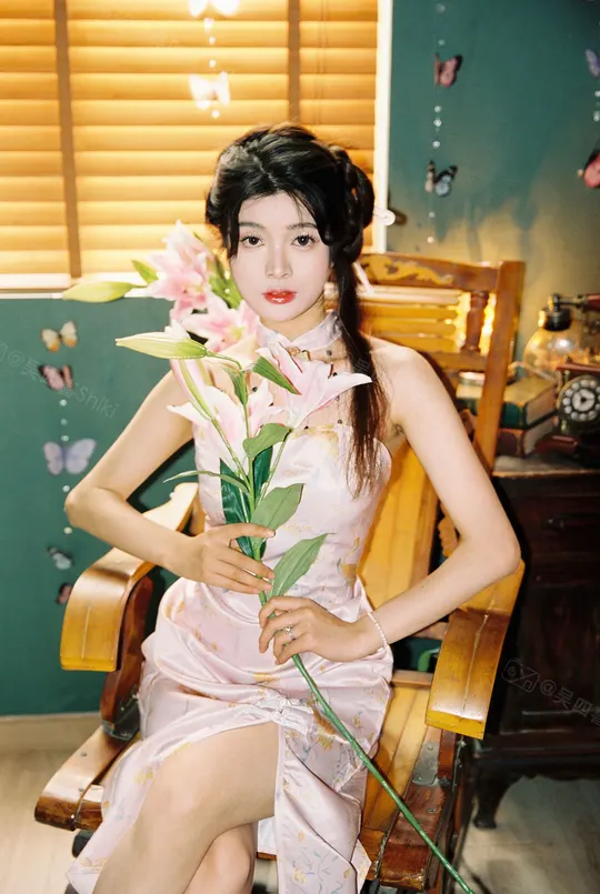 一个穿着粉红色裙子的年轻女子坐在长椅上 手里拿着花。