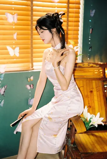 一个穿着白色连衣裙的年轻女子坐在粉红色房间里的一张长椅上