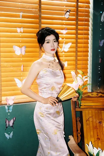 一位穿着传统白色和服的年轻女子 手持扇子 扇子上绘有花和蝴蝶 站在竹墙前。