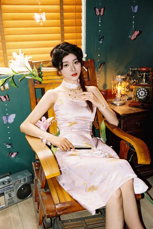 一个穿着粉红色连衣裙的年轻女子坐在一个装饰有花纹的摇椅上