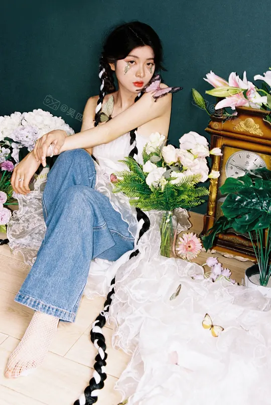 一个坐在地板上 周围环绕着白色花朵和一只钟表的美丽年轻女子。