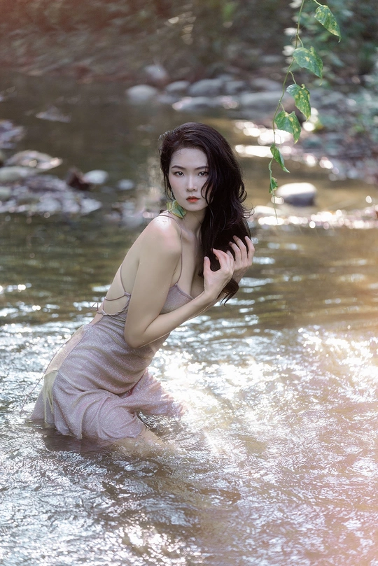 美丽的年轻女子在流动的水中在河里或小溪里摆姿势