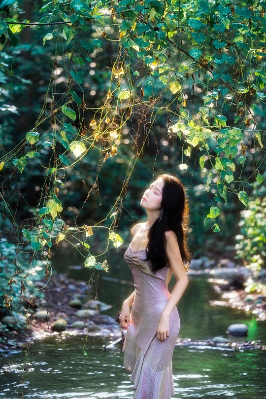 站在河里或小溪里的一位身穿粉色连衣裙的美丽年轻女士