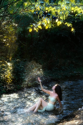 一个年轻的女人坐在森林里的小溪上