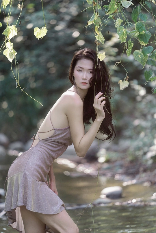 一个穿着连衣裙的年轻女子站在河里或小溪里 在水中摆姿势