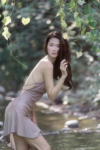 一个穿着连衣裙的年轻女子站在河里或小溪里 在水中摆姿势