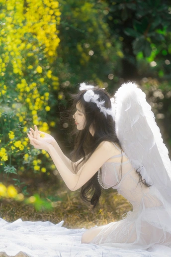 一个穿着天使服装的年轻女孩坐在一片黄花的田野上 双手向外伸展。