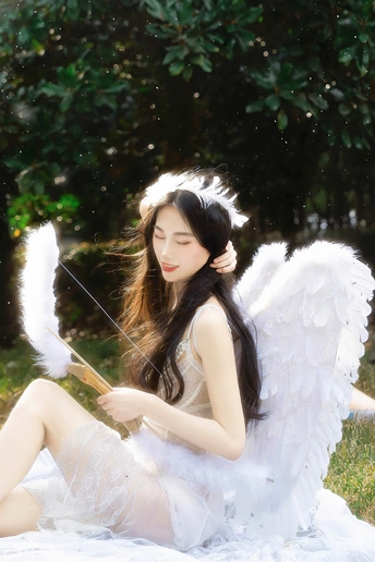 一位有白色翅膀和一本书在草地上的女人