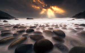 夕阳长时间在海滩上的岩石和水体上的长时间曝光 天空中云朵