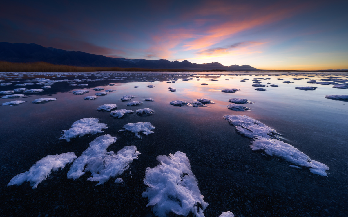 夕阳下冻结的湖泊 天空中云朵 背景中群山