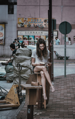 一个年轻女子坐在木凳上 双腿交叉