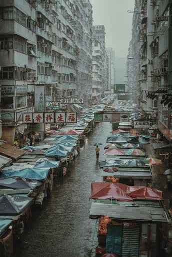 一条湿漉漉的街道 有许多船和人 他们带着伞 还有高大的建筑。