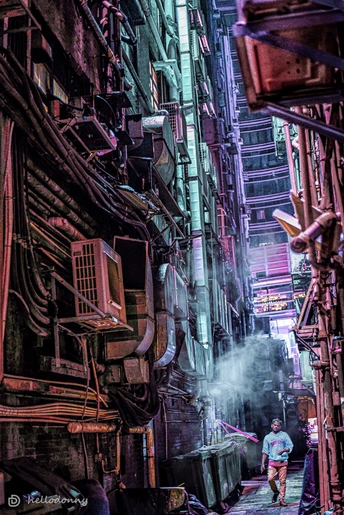 一个人在城市里走在一个巷子里 周围有建筑物。