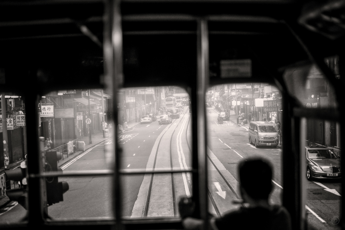 一张黑白照片 展示一个人在繁忙的城市街道上 透过窗户看出去 一辆电车在街道上行驶。