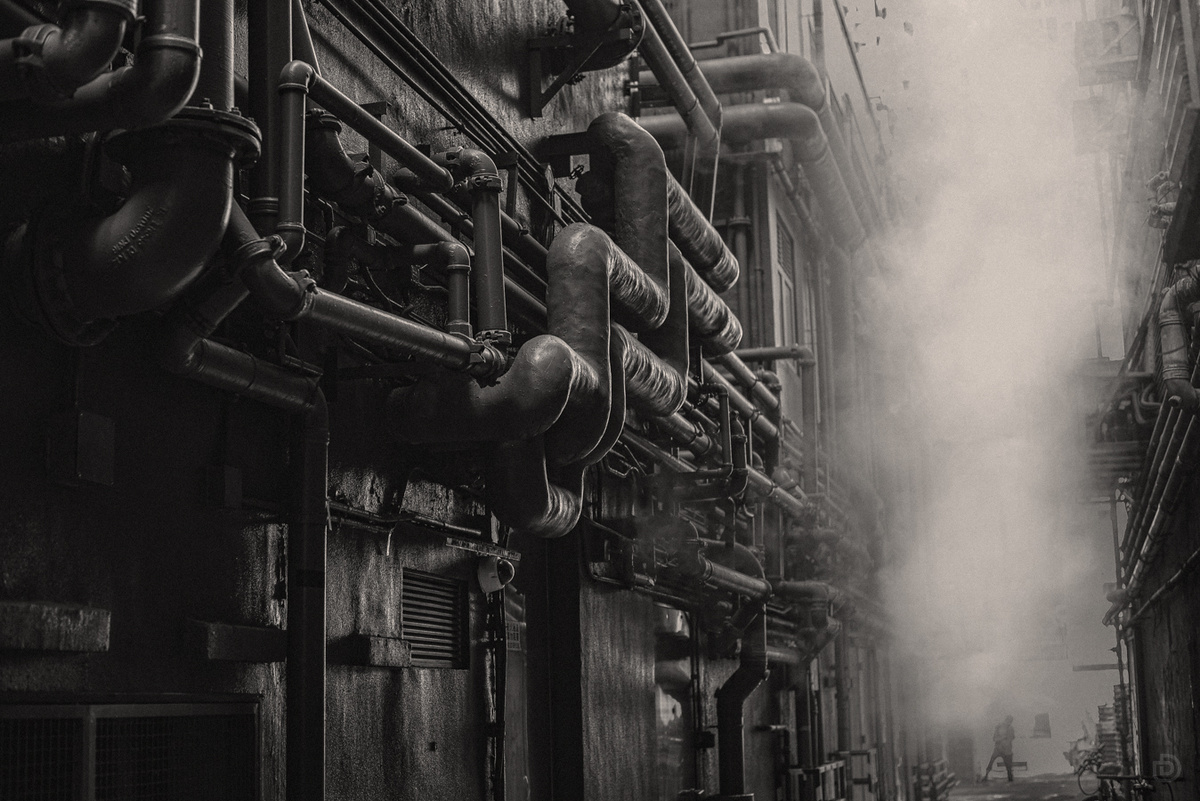 一张黑白照片 展示了城市中的工业管道。