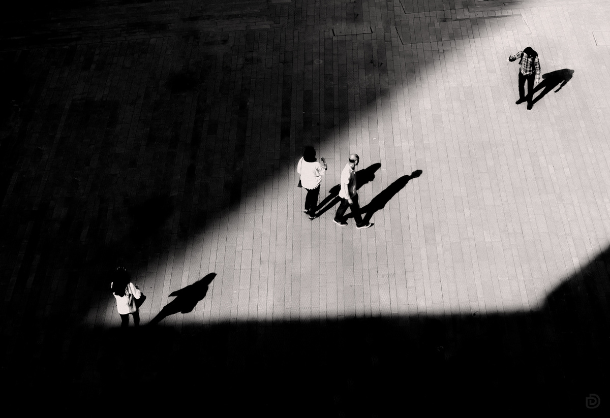 黑白照片中的人们走在一条街道上 有一个人在滑板上的阴影。