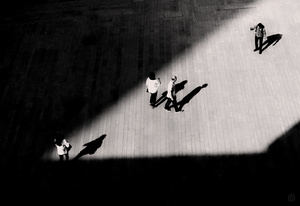 黑白照片中的人们走在一条街道上 有一个人在滑板上的阴影。
