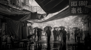 一张黑白照片 人们打着伞在雨中穿过市场。