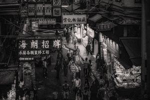 一张黑白照片 描绘了夜晚亚洲城市的一条小巷子里的人们正在行走。