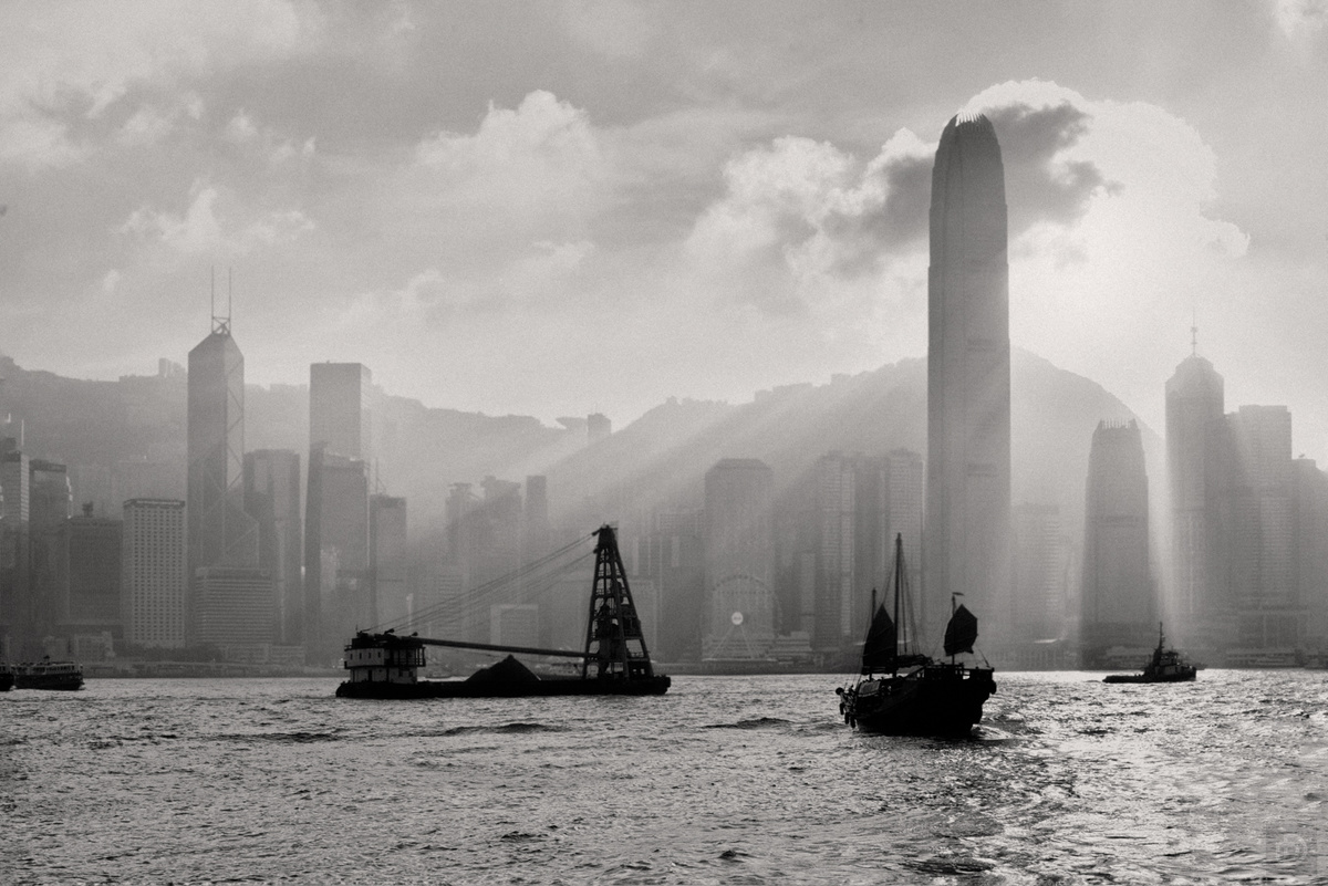 一张黑白照片 城市天际线上有摩天大楼 水面上有船只在航行。