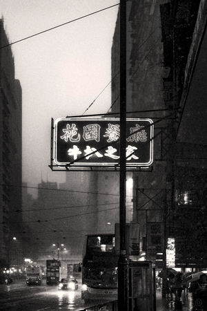 一张夜晚城市街道的黑白色照片 有建筑和街道标志。