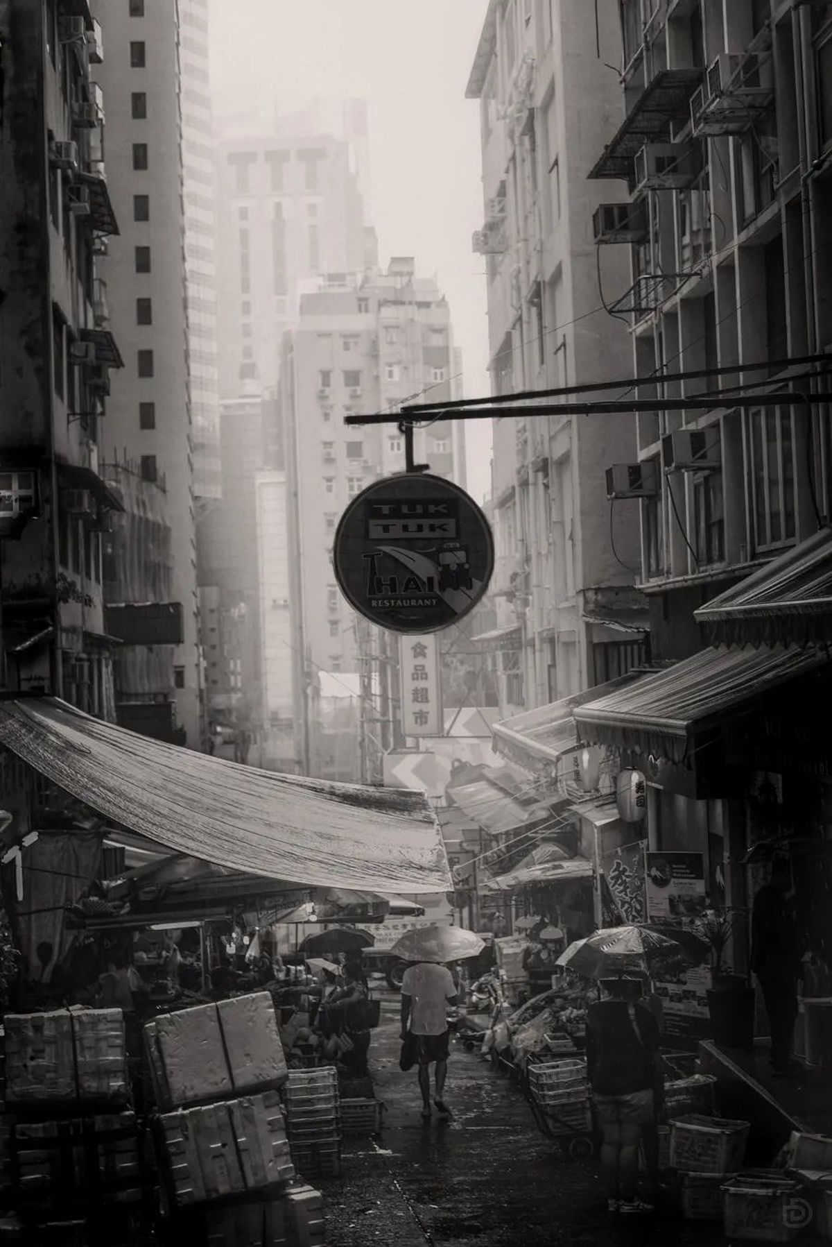 一张黑白照片 展示了一个城市街道 人们在雨中行走 并手持雨伞。