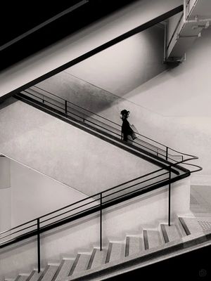 一个黑白照片 一个男子正在走上楼梯通往一个自动扶梯。