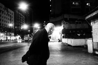 一张黑白照片 一个老人在夜晚走人行道。