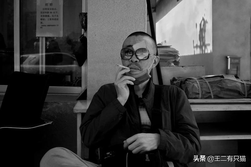 一张黑白照片 一个戴眼镜的男人在公共汽车上抽烟。