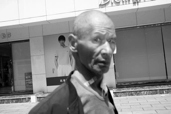 一张黑白照片 一位老人站在一栋建筑前