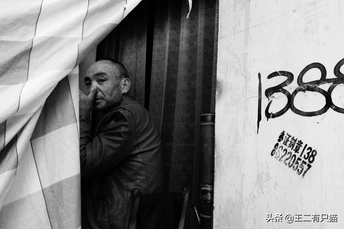 一个黑白相间的男子靠在一栋有涂鸦的墙边