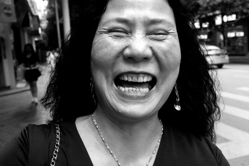 一个站在街上的女人 脸上带着微笑 牙齿露在外面。