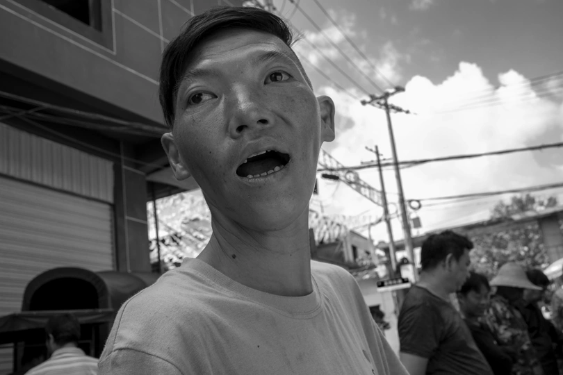 一位惊讶地表情的小伙子张开嘴巴 人们站在背景中。