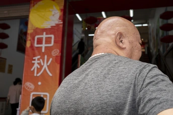 一个秃顶男子在健身房看手机