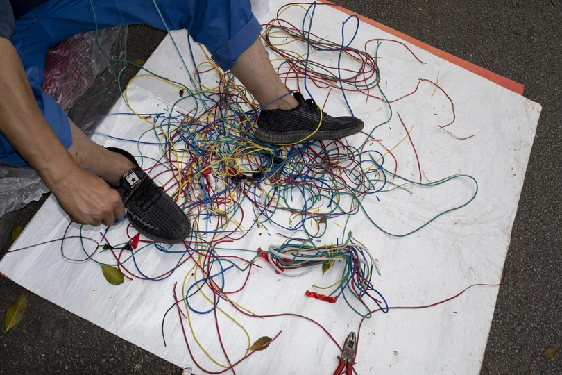 一个穿着鞋子的男人站在一堆电线堆上