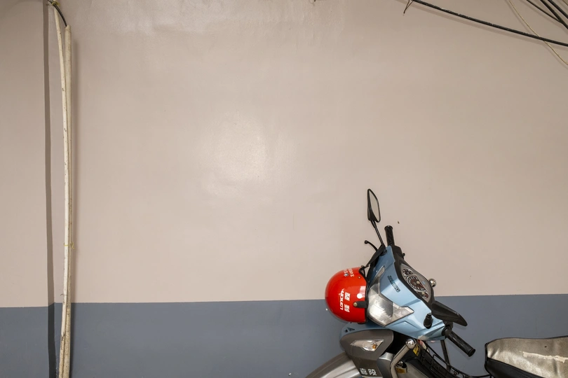 一辆红色的摩托车停在旁边有一堵墙的房间里