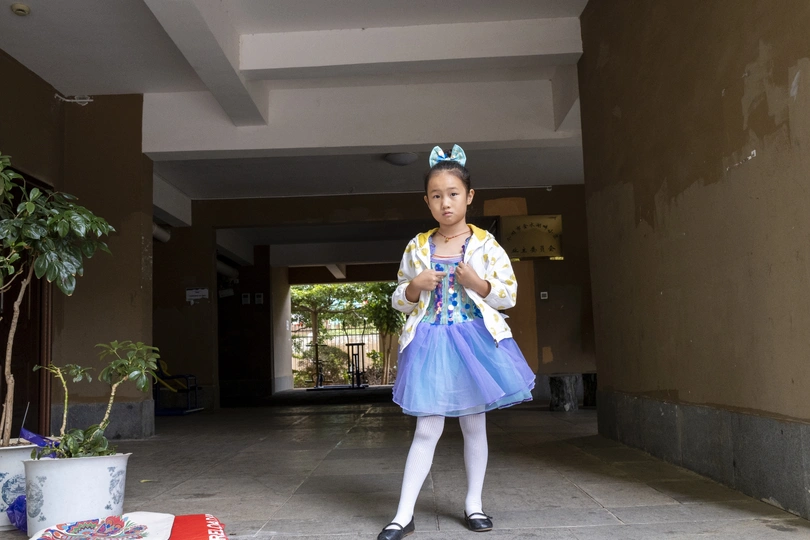 一个小女孩穿着蓝色裙子站在门口