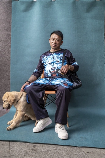 一个老人坐在一只狗旁边的蓝色椅子上