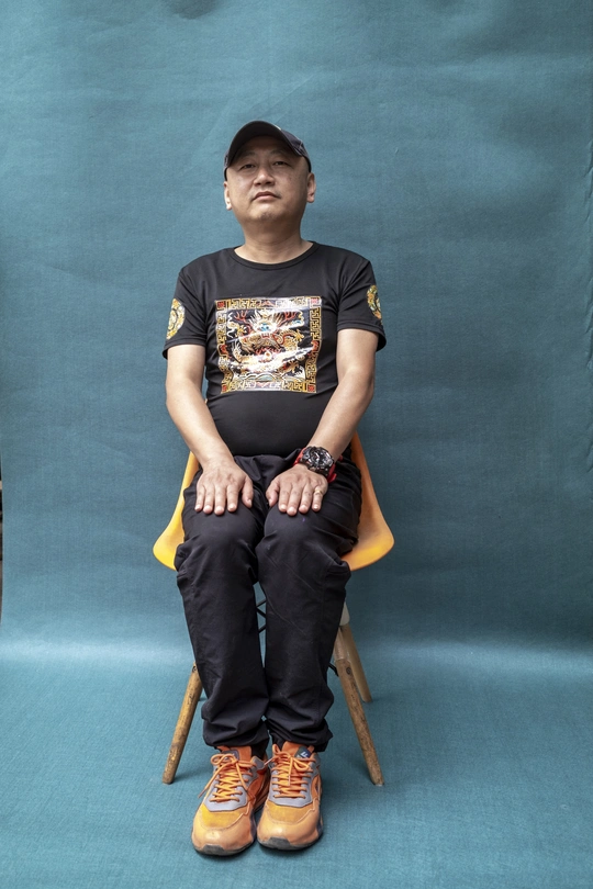 一个穿着黑色衬衫和黄色鞋子的年轻人坐在蓝色的椅子上。