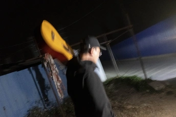 一个穿黑衣服的人拿着一个黄色的飞盘在夜晚