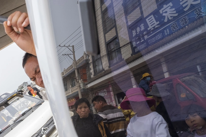 一个人在公共汽车窗口向外看 街上的人们和孩子们在忙碌地穿梭。