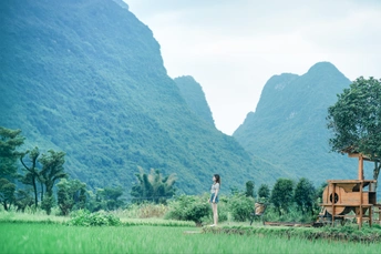 一位站在绿色原野上的女人 背景是山脉。