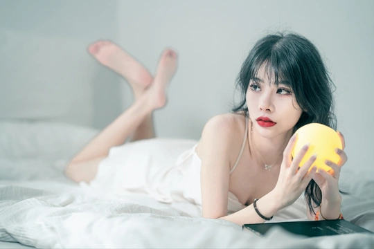 一位年轻女子躺在白色床上