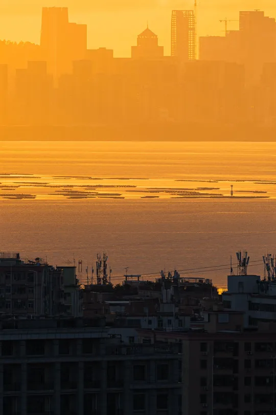 太阳落在一个城市天际线前的水域上。