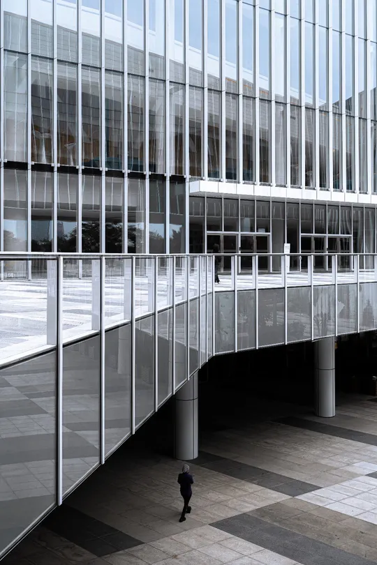 一个人穿过一座现代办公楼的大窗户庭院