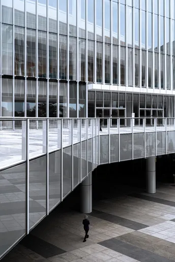 一个人穿过一座现代办公楼的大窗户庭院