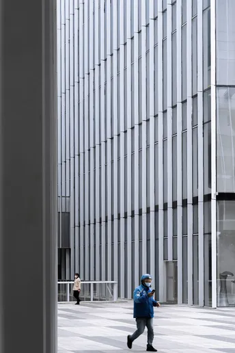 一个人穿着蓝色走过一座高大的办公楼