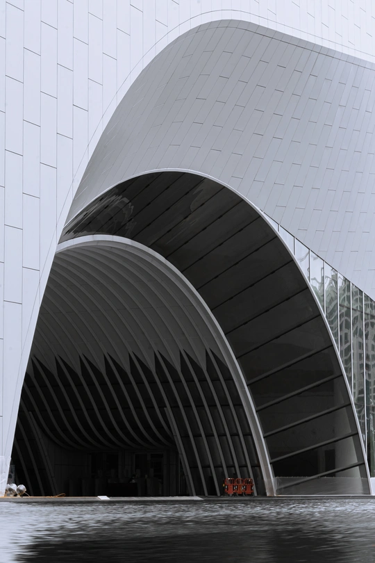 这座建筑是白色的大型建筑 具有现代建筑风格 并在水中有一艘船。