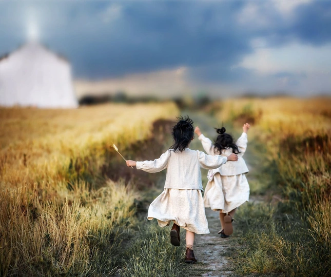 两个穿白色连衣裙的女孩沿着田地小径跑过 背景有一座谷仓。