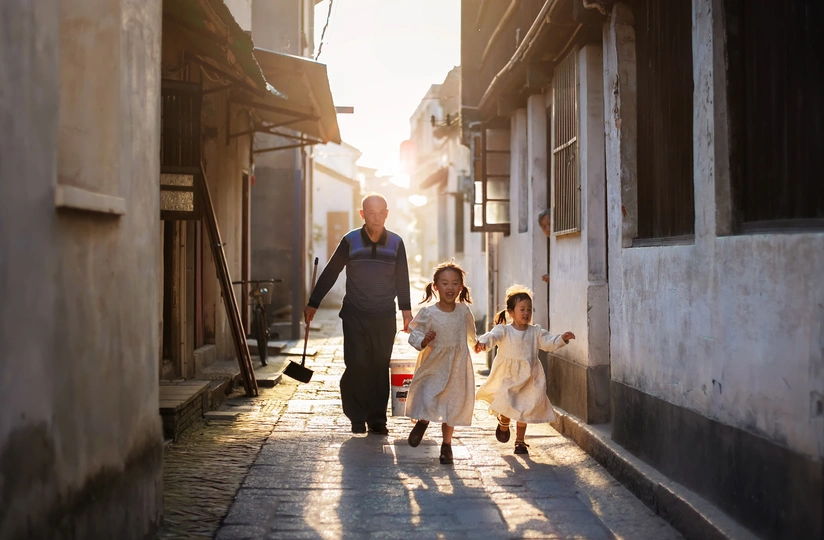 一个小女孩和她的家人在一条狭窄的街道上手拉手走
